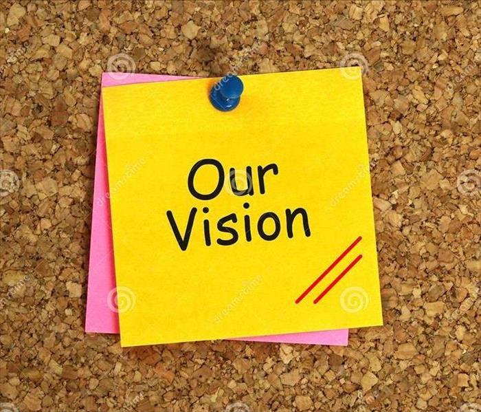 Sticky note with "Our Vision" pinned on a cork board.