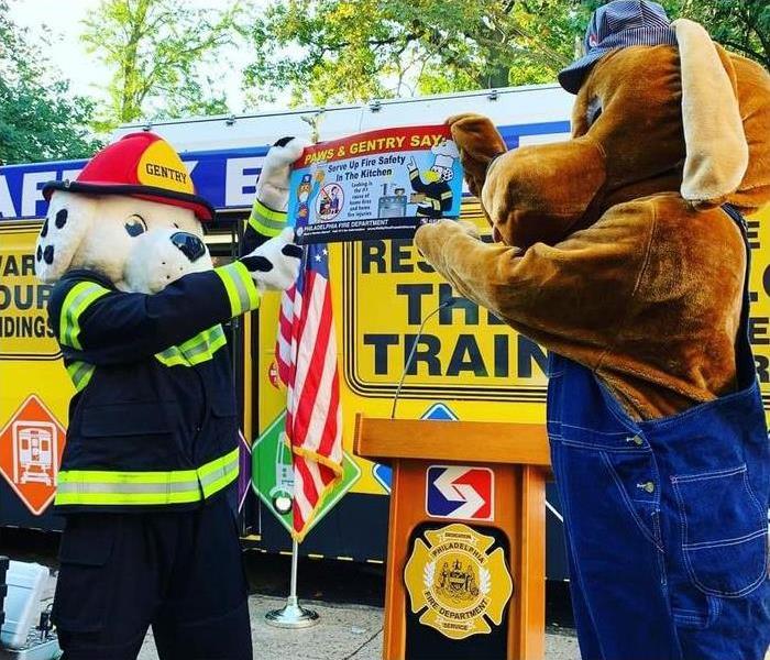 Dalmation dressed as fire fighter and other dog holding up a sign with the Fire Prevention Week campaign photo 