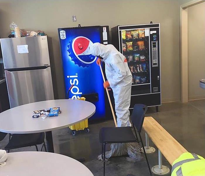 A worker in PPE mops the floor as part of an emergency cleaning in Oxford, MS.