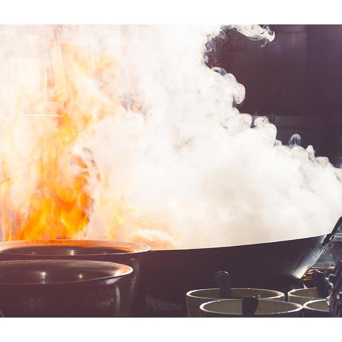 A fire burns in a hot skillet. Smoke surrounds the photo.